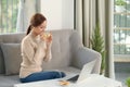 Enjoy weekend. Asian girl relaxing, drinking coffee and using laptop, sitting on couch at home Royalty Free Stock Photo