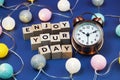 Enjoy Your Day alphabet letter and alarm clock decorate with LED cotton ball on blue background