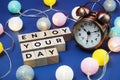 Enjoy Your Day alphabet letter and alarm clock decorate with LED cotton ball on blue background