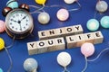 Enjoy Your Life alphabet letter and alarm clock decorate with LED cotton ball on blue background