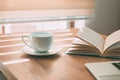 Enjoyable home office workspace with coffee cup, open book and laptop computer