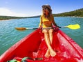 Enjoyed female people sitting on a red kayak traveling on a blue water lake. Wide angle view of active tourist woman in summer