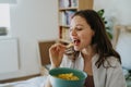 Enjoying crunchy chips. Woman has cravings for potato chips, eating with closed eyes, holding bowl. Royalty Free Stock Photo