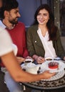 Young couple spending time in outdoor cafe while waitress serving cake Royalty Free Stock Photo