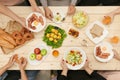 Enjoying dinner with friends. Top view of group of people having dinner together while sitting at wooden table Royalty Free Stock Photo