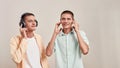 Enjoying favourite playlist. Two young caucasian twin brothers in casual wear listening music in headphones and wireless Royalty Free Stock Photo