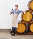 Enjoying a fine red wine. A young wine maker holding a glass of red wine while leaning on a barrel. Royalty Free Stock Photo