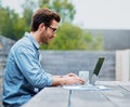 Enjoying the freedoms of freelancing. Shot of a handsome young man using a laptop outdoors. Royalty Free Stock Photo