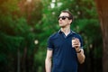 Enjoying fresh coffee. Handsome young man in casual wear holding disposable cup and smiling while walking through city Royalty Free Stock Photo
