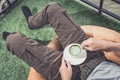 Enjoying fresh coffee. Man wearing cargo pants and holding cup while relaxing on couch at home Royalty Free Stock Photo