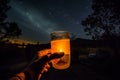 Enjoying glass of orange juice at campsite with cozy campfire and starry night sky. Generative AI.