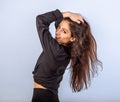 Enjoying happy toothy laughing woman posing in black shirt standing and holding hands in brown hair on studio blue background with Royalty Free Stock Photo