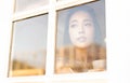 Enjoying her fresh coffee.Portrait of beautiful young Asian woman drinking coffee in the morning and looking through window while Royalty Free Stock Photo