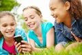 Enjoying her new smartphone. Three little girls spending time together and sharing a smartphone while outdoors. Royalty Free Stock Photo