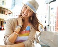 Enjoying her vacation. A lovely young woman wearing a hat sitting at a sidewalk cafe in the city and smiling at the Royalty Free Stock Photo