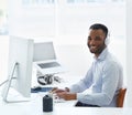 Enjoying his playlist at work. A handsome young african american businessman working at his desk. Royalty Free Stock Photo