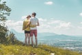 Enjoying the idyllic mountain landscape: Couple is standing on idyllic meadow and enjoying the view over the far away city of Royalty Free Stock Photo