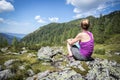 Enjoying the idyllic mountain landscape: Girl is sitting on a rock and resting