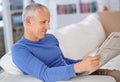 Enjoying an interesting read. a mature man sitting on his living room sofa reading a newspaper. Royalty Free Stock Photo