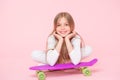 Enjoying life in the extreme speed. Happy small extreme athlete relaxing at violet penny board on pink background. Cute