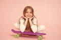 Enjoying life in the extreme speed. Happy small extreme athlete relaxing at violet penny board on pink background. Cute