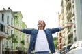 Enjoying life happy mature man spread his hands wide standing on the street of old town wearing white denim shirt. Happy Royalty Free Stock Photo