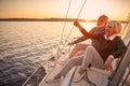 Enjoying luxury life. Beautiful happy senior couple in love relaxing on the side of sailboat or yacht deck floating in