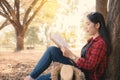 Enjoying moment hipster woman reading a book and sitting under the big tree on park Royalty Free Stock Photo