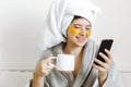 Enjoying morning concept. Happy girl drinking coffee and browsing internet. Beautiful young woman with golden eye patches in Royalty Free Stock Photo