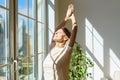 Happy senior woman enjoying life, standing in front of window with closed eyes and smiling Royalty Free Stock Photo