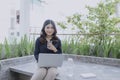 Enjoying nice time on fresh air. Beautiful young woman working on her laptop and smiling while sitting in floor on her outdoor Royalty Free Stock Photo