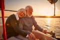 Enjoying sailing at sunset. Happy senior couple, elderly man and woman holding hands, hugging and relaxing while sitting Royalty Free Stock Photo