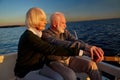 Enjoying sailing together. Side view of beautiful senior couple, elderly man and woman sitting on the side of sailboat Royalty Free Stock Photo