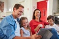 Enjoying some digital family entertainment. smiling parents sitting with their young son and daughter on their living Royalty Free Stock Photo