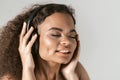 Enjoying the sound in professional earphones young African-American girl listening music wearing black top isolated on Royalty Free Stock Photo