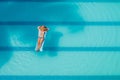 Enjoying suntan. Vacation concept. Top view of slim young woman in bikini on the blue air mattress in the big swimming pool Royalty Free Stock Photo