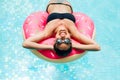 Enjoying suntan woman in black bikini on the inflatable mattress in the swimming pool Royalty Free Stock Photo