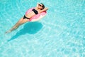 Enjoying suntan woman in black bikini on the inflatable mattress in the swimming pool Royalty Free Stock Photo