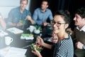 Enjoying a team lunch. Portrait of a young office worker eating lunch with coworkers at a boardroom table. Royalty Free Stock Photo