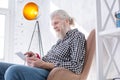 Pleasant senior man scrolling social media timelines on tablet