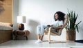 Beautiful young smiling african american woman working on laptop while sitting in bcomfortable chair at home Royalty Free Stock Photo