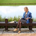 Enjoying a time-out in the park. Shot of an attractive blonde woman reading a book during her lunch break on a park Royalty Free Stock Photo