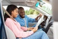 Happy black couple looking at paper map sitting inside car Royalty Free Stock Photo