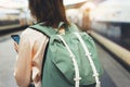 Enjoying travel. Young hipster woman waiting on the station platform with backpack on background electric train using smartphone Royalty Free Stock Photo