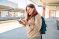 Enjoying travel. Young pretty woman waiting on the station platform with backpack on background electric train using Royalty Free Stock Photo