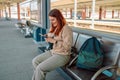 Enjoying travel. Young pretty woman waiting on the station platform with backpack on background electric train using Royalty Free Stock Photo