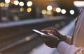 Enjoying travel. Young woman waiting on station platform on background light electric moving train using smart phone in night Royalty Free Stock Photo