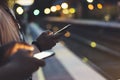 Enjoying travel. Young woman waiting on station platform on background light electric moving train using smart phone in night Royalty Free Stock Photo