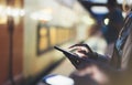 Enjoying travel. Young woman waiting on station platform on background light electric moving train using smart phone in night Royalty Free Stock Photo