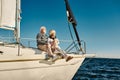 Enjoying vacation. Happy senior family couple sitting on the side of a sail boat or yacht deck floating in a calm blue Royalty Free Stock Photo
